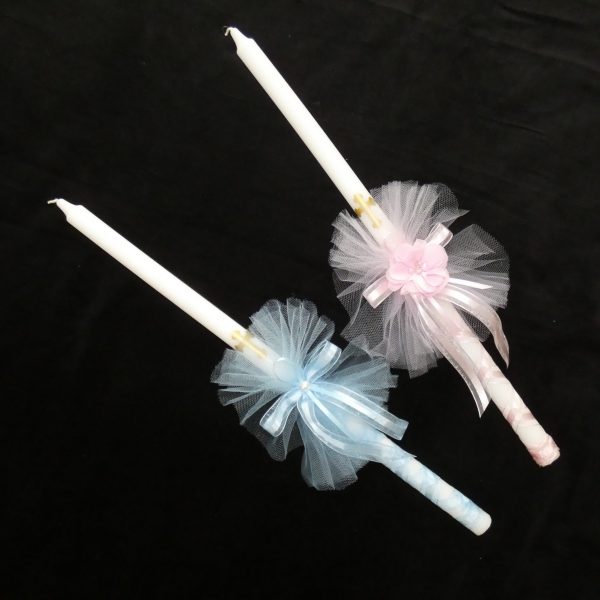 Two Orthodox baptismal candles (from left to right) with blue and pink ribbons and tulle.