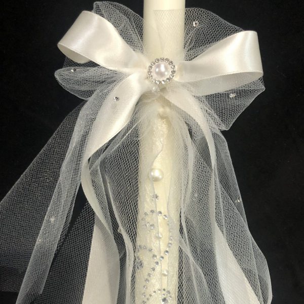 Closeup of the satin bow and crystal beading on an ivory wedding candle.
