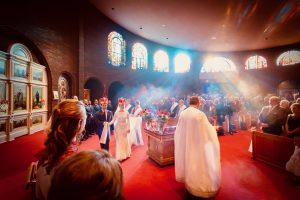 Couple walks around the altar table while incense hangs in the air and reflects the sunlight.