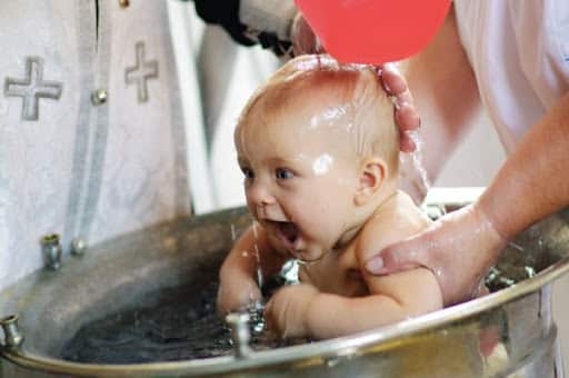 Baby being immersed in water during Orthodox baptism.