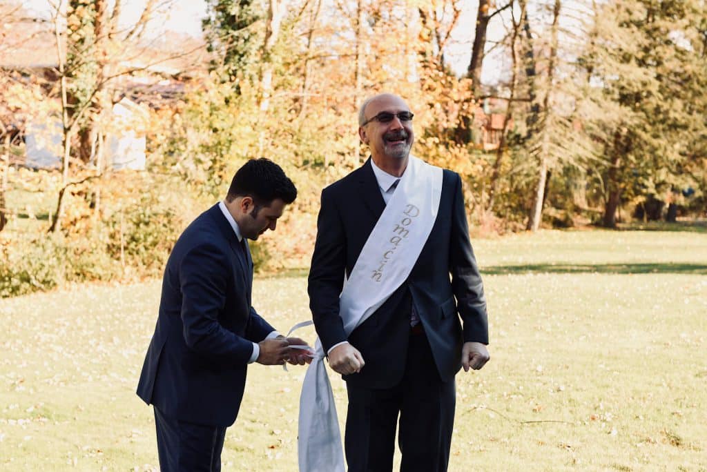 Groom putting a wedding sash on someone