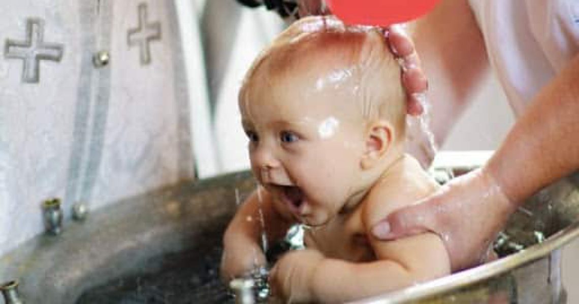 Baby being immersed in water during Orthodox baptism.