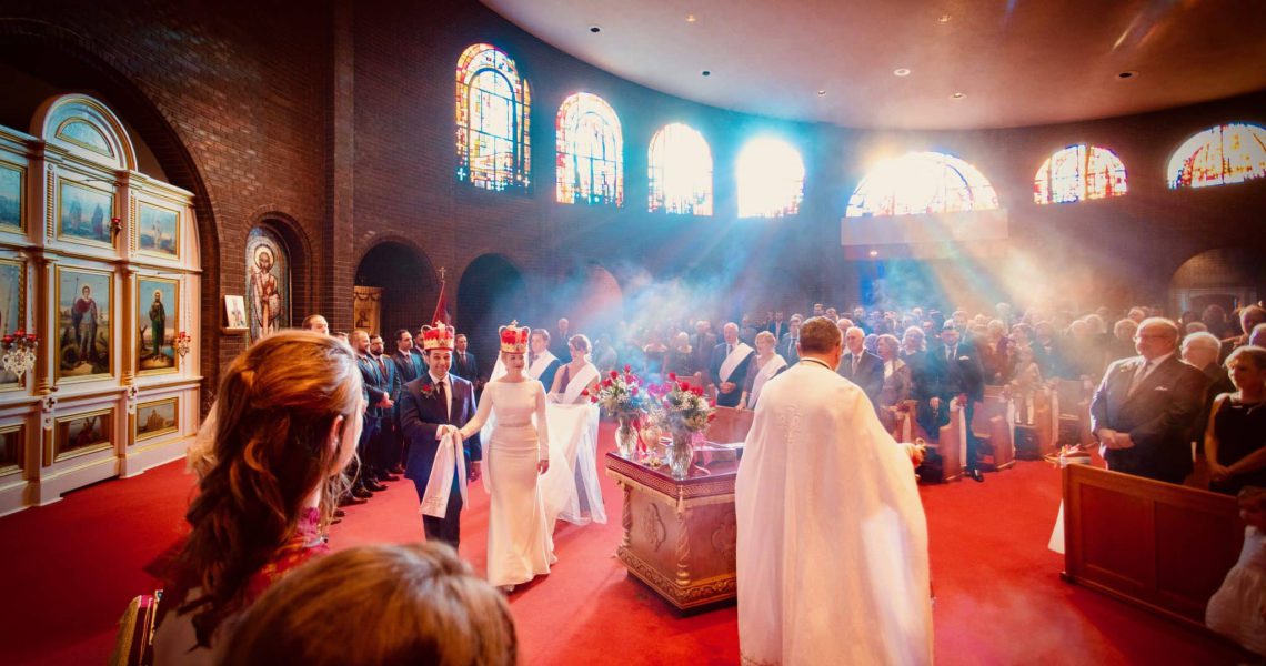 Couple walks around the altar table while incense hangs in the air and reflects the sunlight.